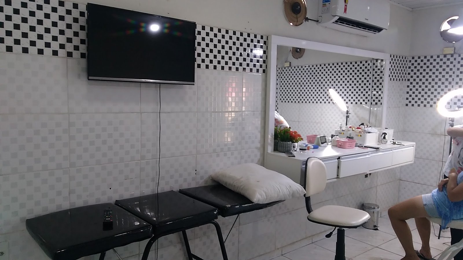 Estação de atendimento do studio, com bancada, espelho e luz para cílios e sobrancelhas