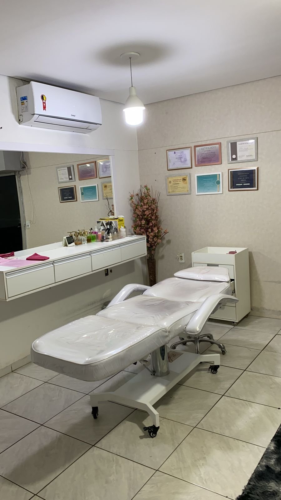 Sala de procedimentos do studio, com maca e certificados na parede
